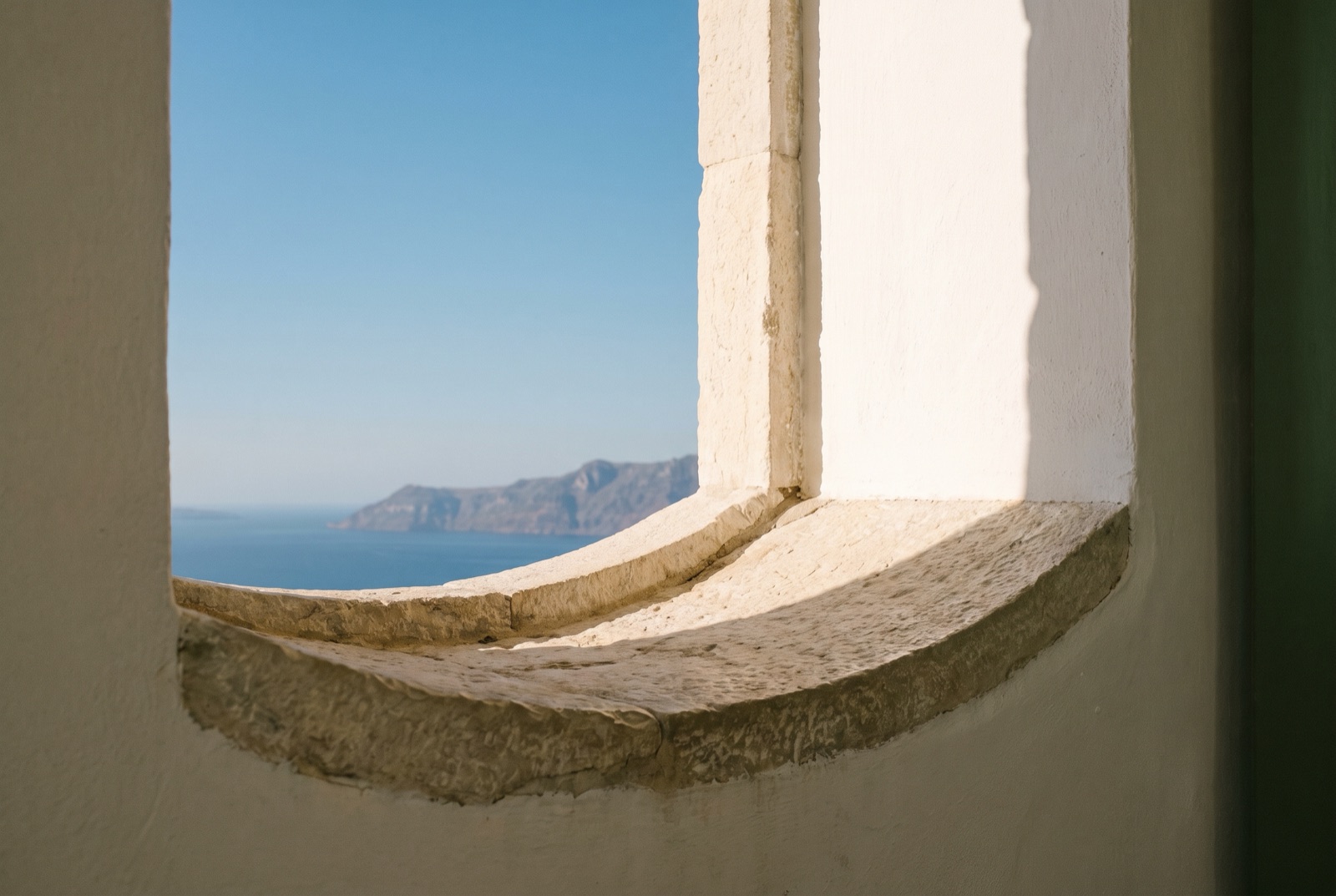 A single closed folder on the stone window sill, with the coast in the background