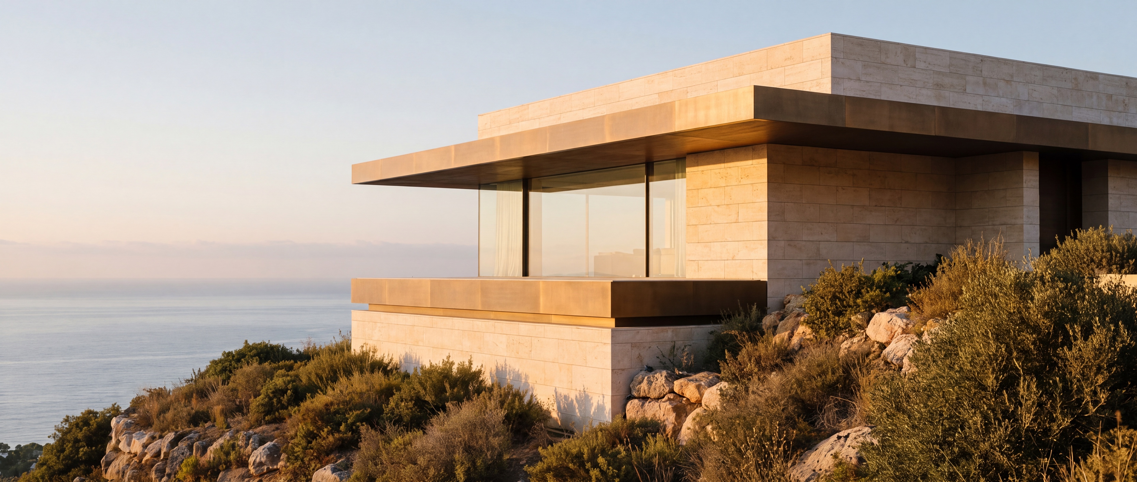 Gran edificio escultórico mediterráneo contemporáneo que emerge de un paisaje de roca natural sobre el mar cerca de Marbella, a la luz del atardecer.