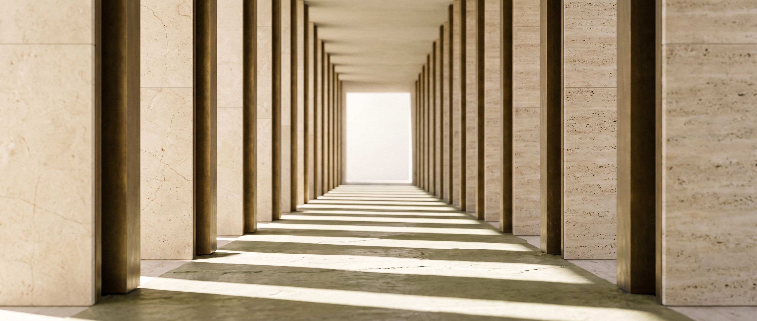Larga galería arquitectónica de columnas de piedra caliza perfectamente alineadas que se pierde en perspectiva hacia la luz.